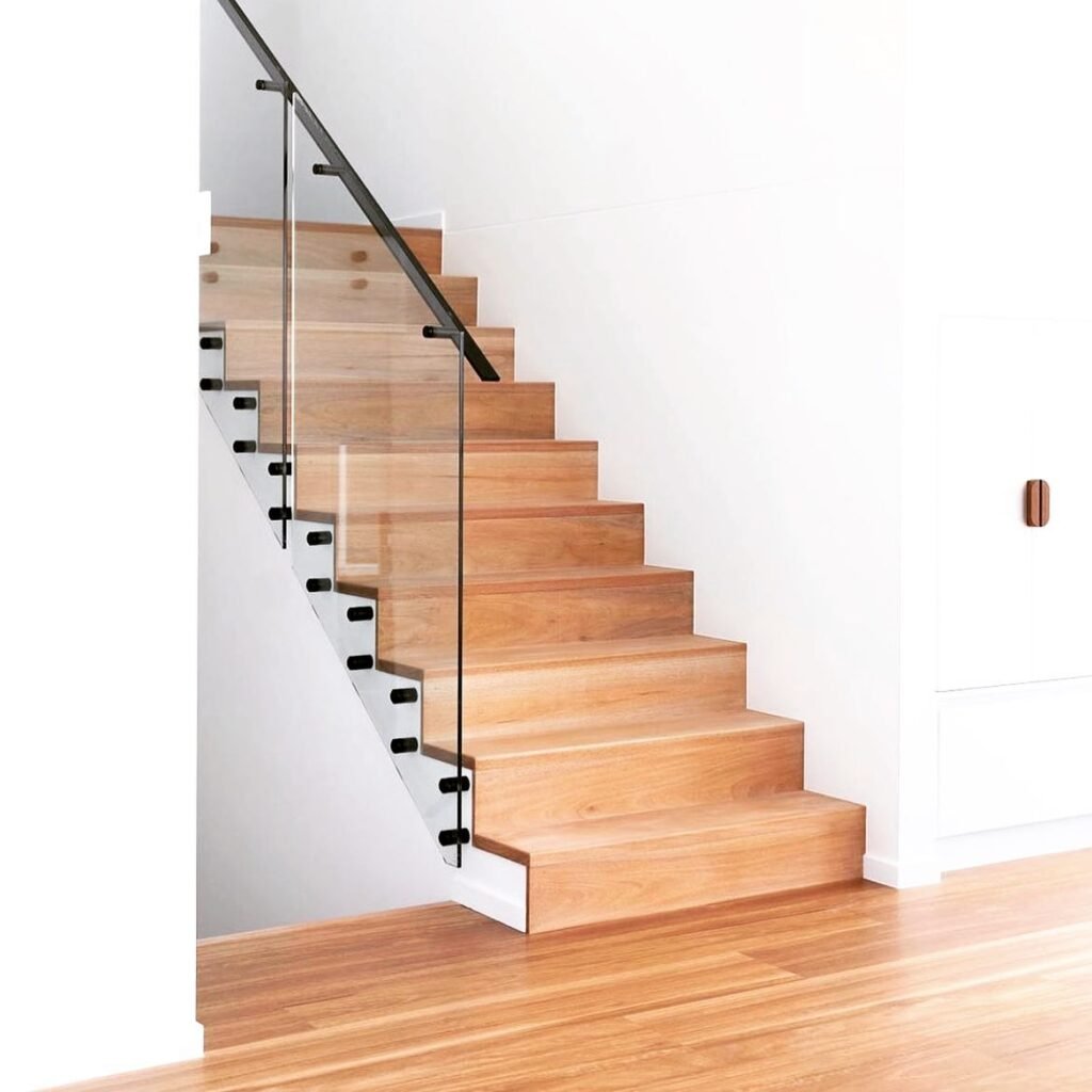 Custom hardwood staircase with glass railing and matching wood flooring