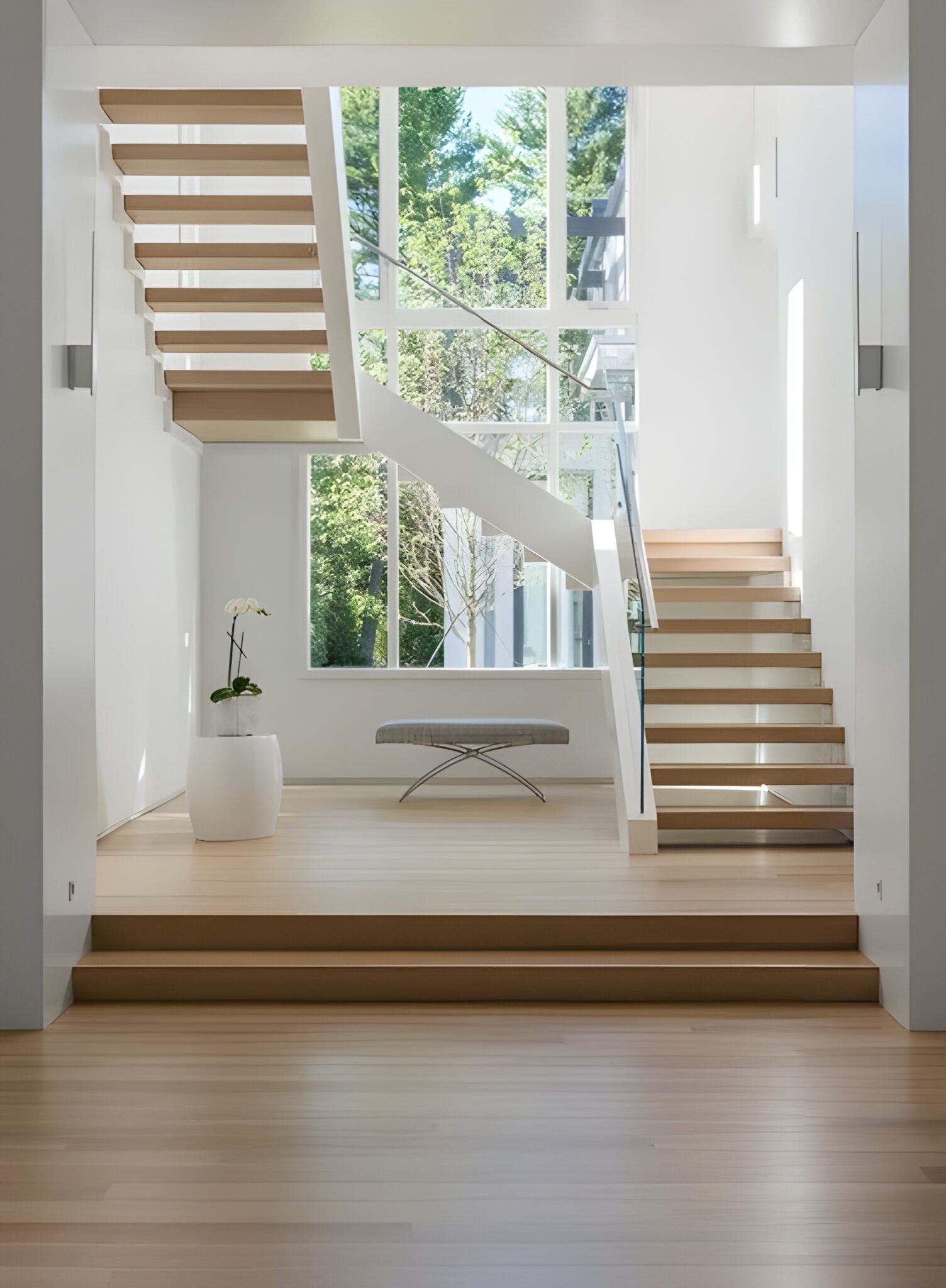 Bright open staircase with floating oak stair treads and a glass railing