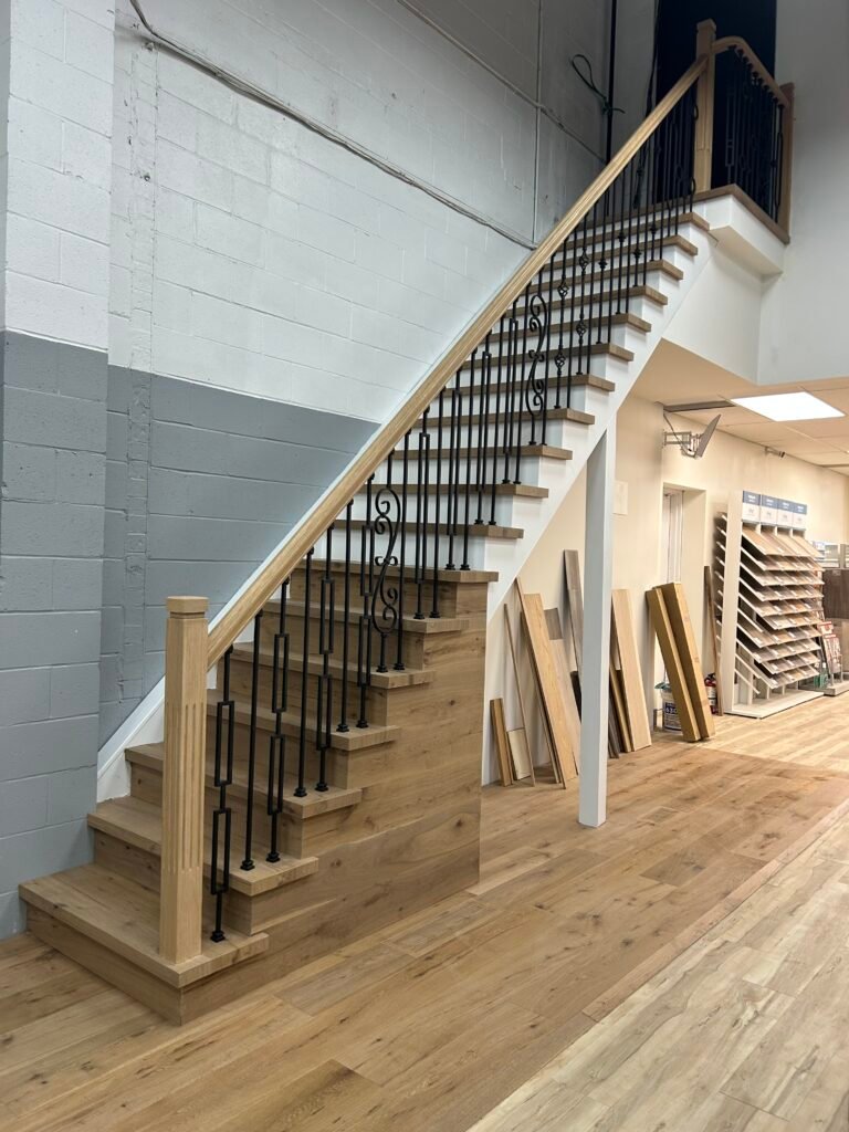 Custom oak staircase with wrought iron balusters in a stair-parts showroom