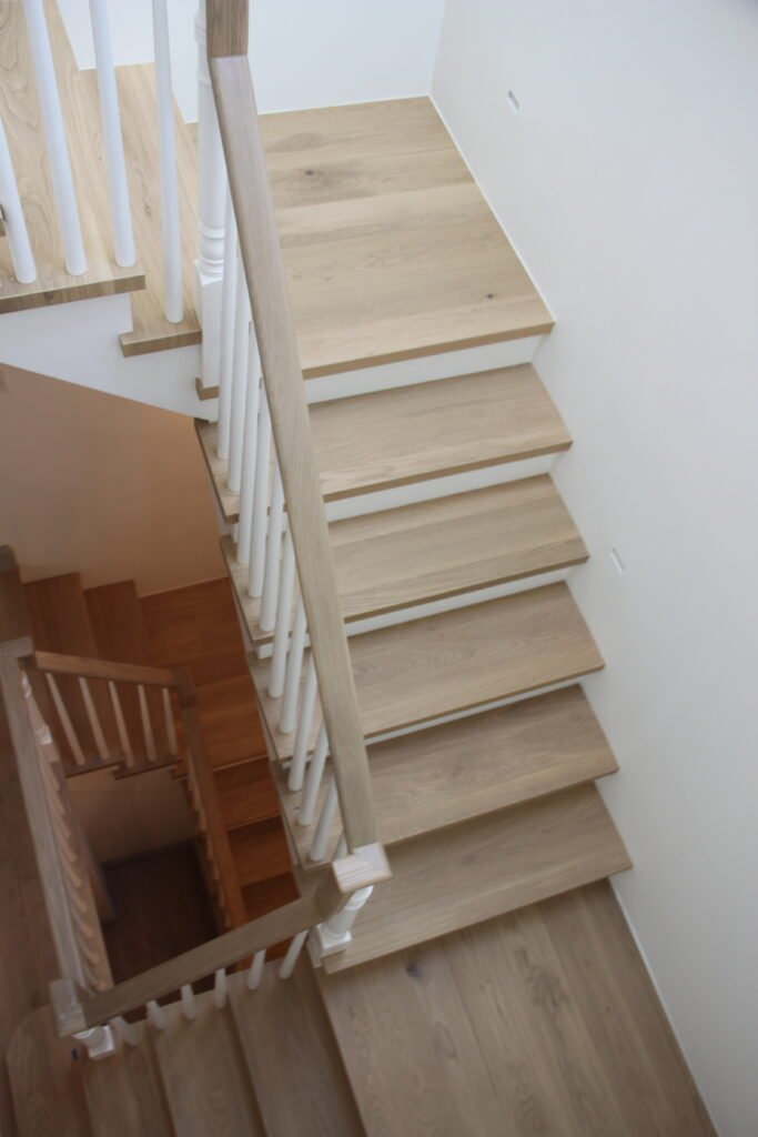 Overhead view of custom oak stair treads with white balusters and matching hardwood flooring
