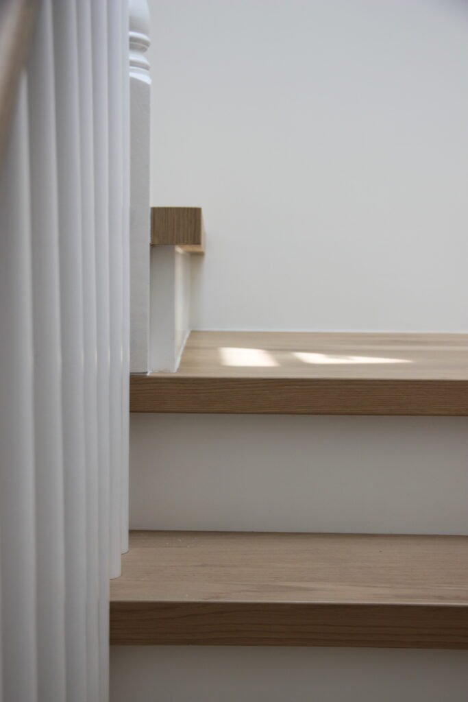 Close-up of custom oak stair treads with white balusters and painted risers