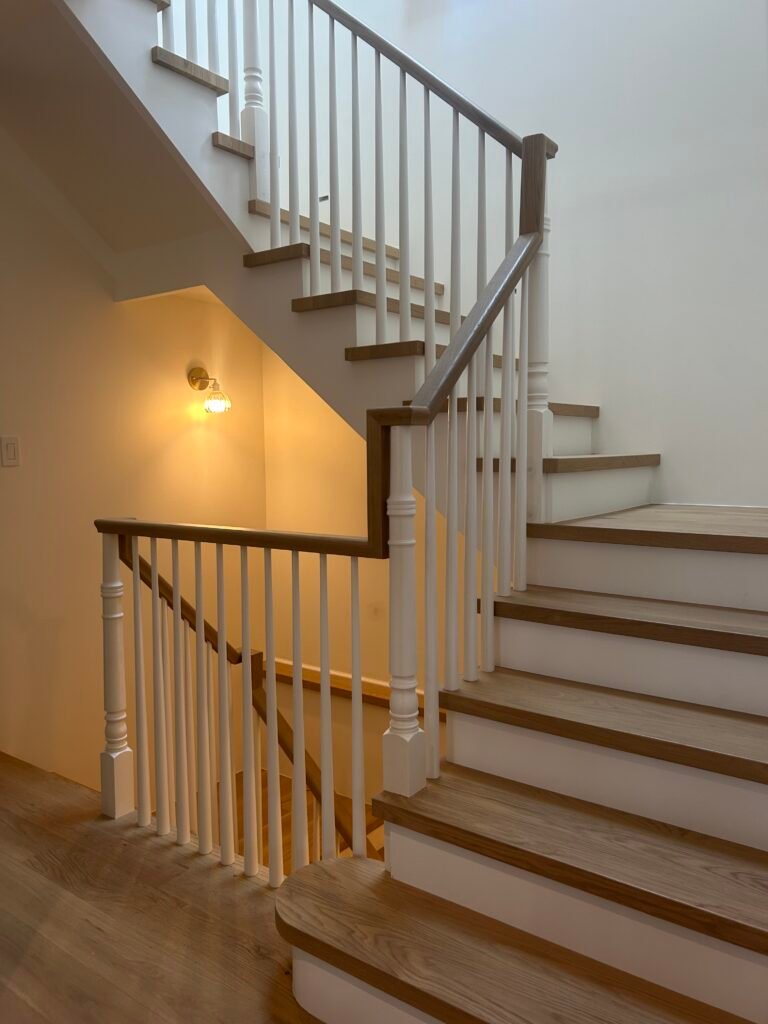 Custom oak staircase with white balusters and dark wood handrail in a two-story foyer