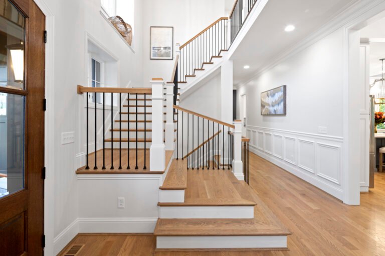 Custom stair products with matching hardwood stair treads, white risers, and black railings in a modern home.