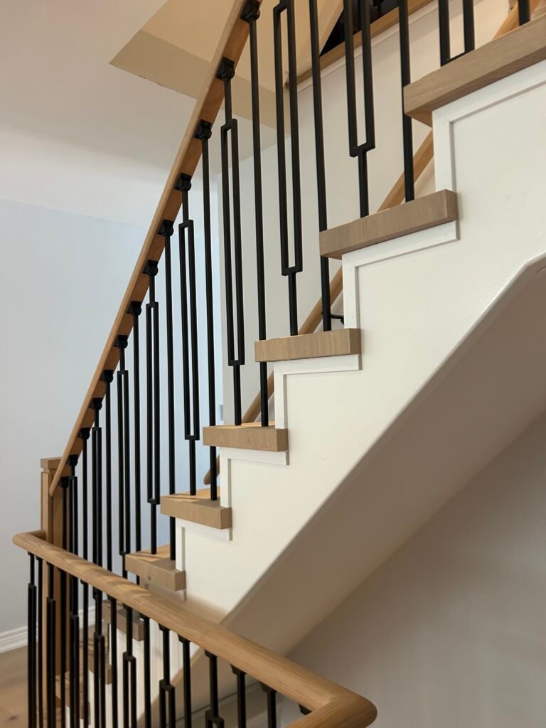 Custom oak staircase with modern black metal balusters and white risers