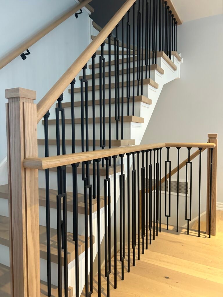 Custom oak staircase with black metal balusters and matching oak handrail and newel posts